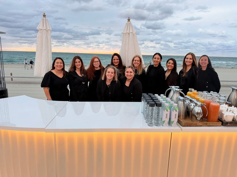 Multi-artist live event calligraphy and engraving team at a beachfront luxury brand activation in Miami, dressed in black and working together for a high-volume personalization event.