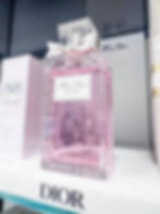 Pink Miss Dior Rose N' Roses perfume bottle with hand engraved floral design by Amanda Elliott luxury Chicago calligrapher and engraver, a bow on top, and branded text, set on a white shelf.