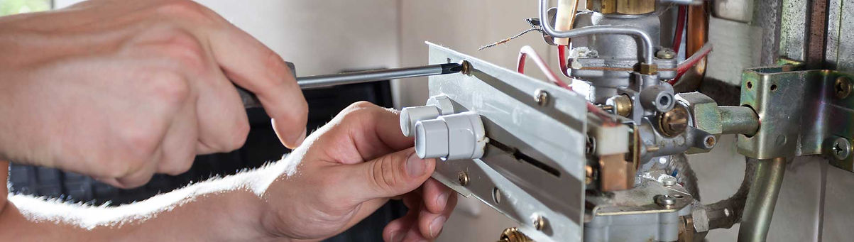 Repairman Fixing a Gas Water Heater with a Screwdriver