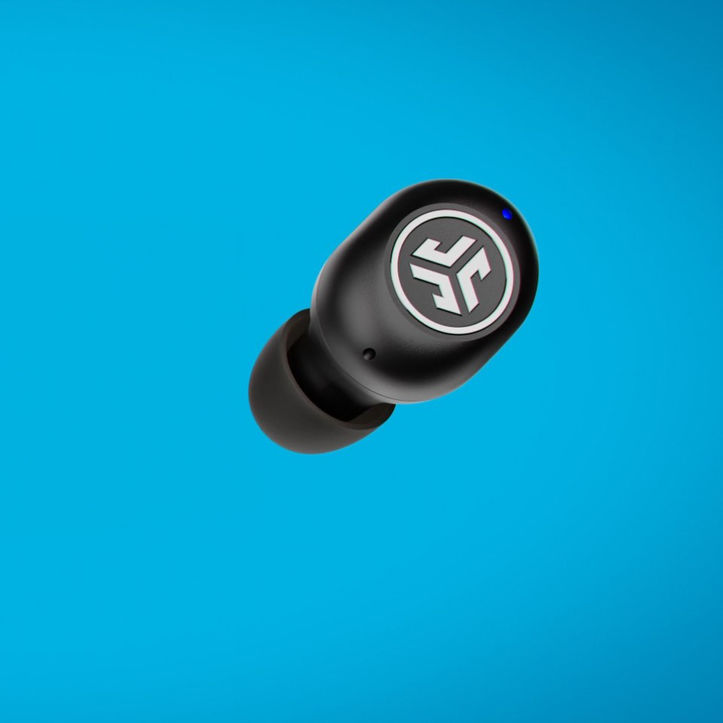 JLab JBuds Mini earbud at an angle on bright blue