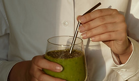 Female hands holding a glass of green smoothie with eco-friendly reusable metallic straw_e