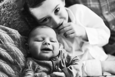 brother smiling with newborn baby