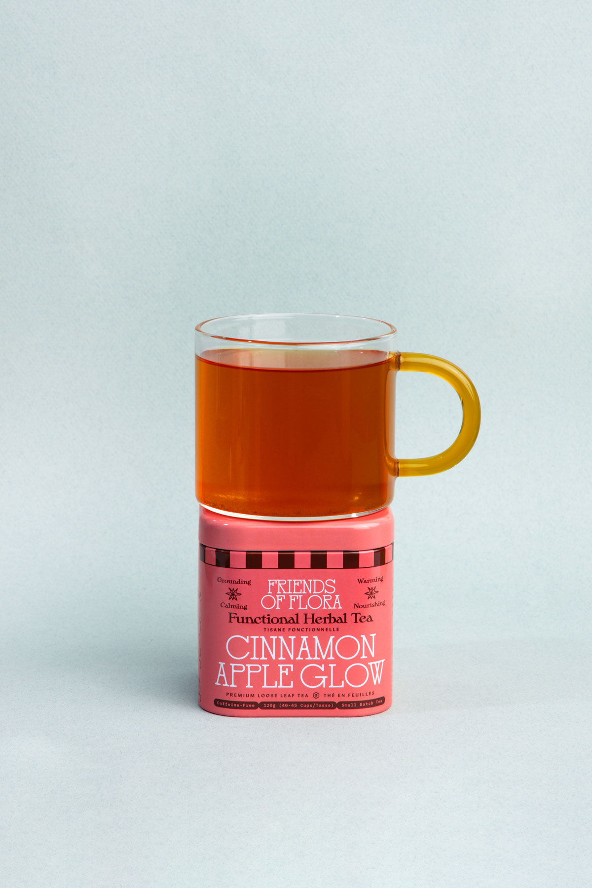 Closed tin of Cinnamon Apple Glow with a brewed cup of cinnamon apple tea on top