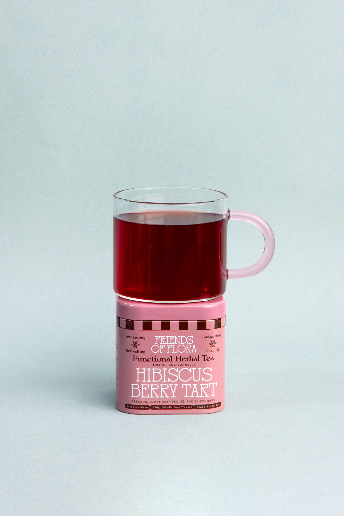Closed aluminum tin of Hibiscus Berry Tart with a brewed cup of hibiscus berry tea on top