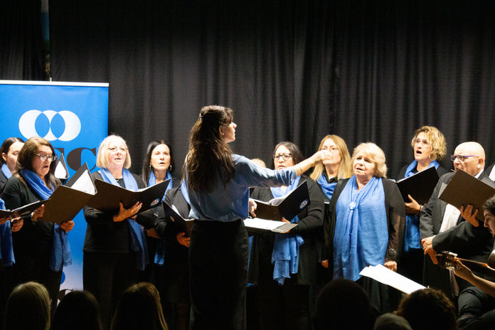 Camila Pérez Lacha conducting a choir during a live performance.