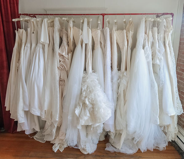 Curated vintage wedding dresses on a rack inside a Denver bridal boutique, with lace, silk, and one-of-a-kind heirloom dress