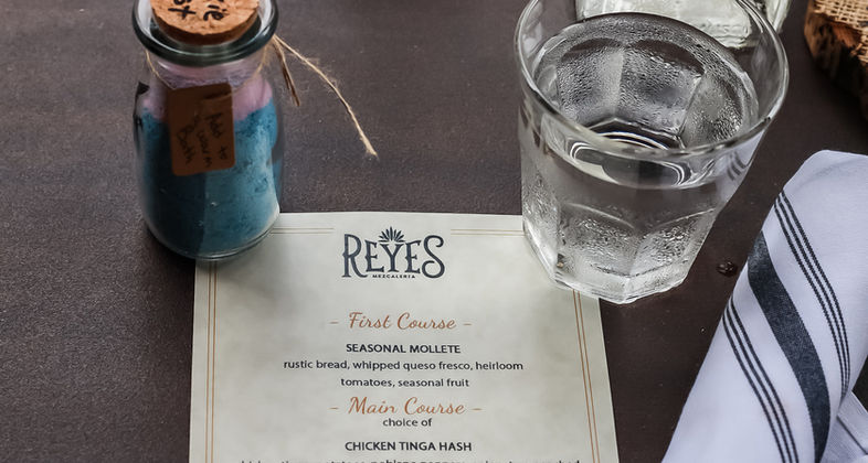 Menu from private event with a party favor, glass of water, silverware rollup