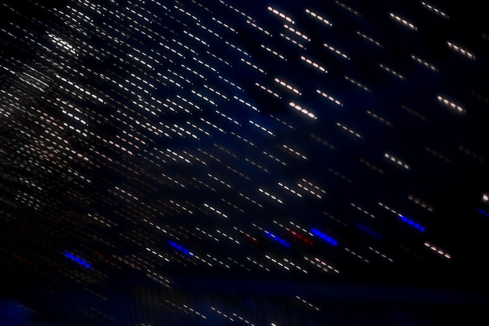 An abstract, intentional camera movement photograph featuring thousands of short, dashed white light streaks running diagonally across a dark navy and black background, mimicking a digital data rain