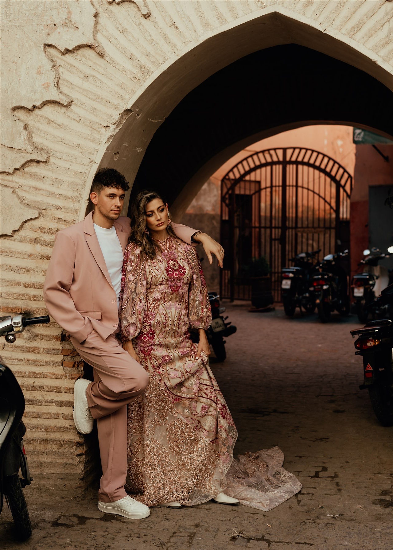 A chic, editorial couple cuddling in the streets of Marrakech wearing a pink suit and a pink wedding dress