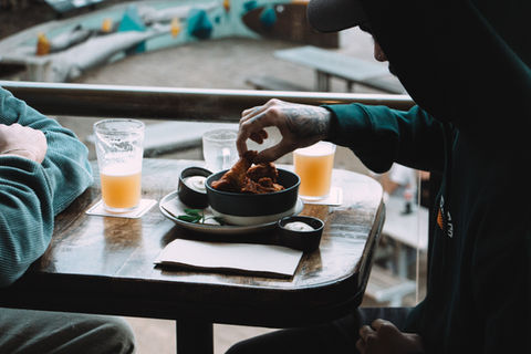 Guests eating buffalo wings with tap beer.