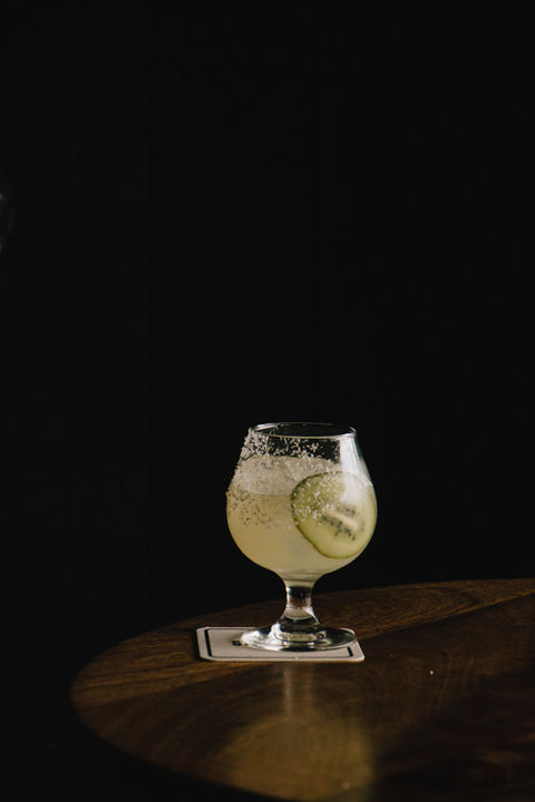 Kiwifruit cocktail served in a brandy glass with coconut salt rim.