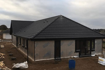 A house under construction with a black roof