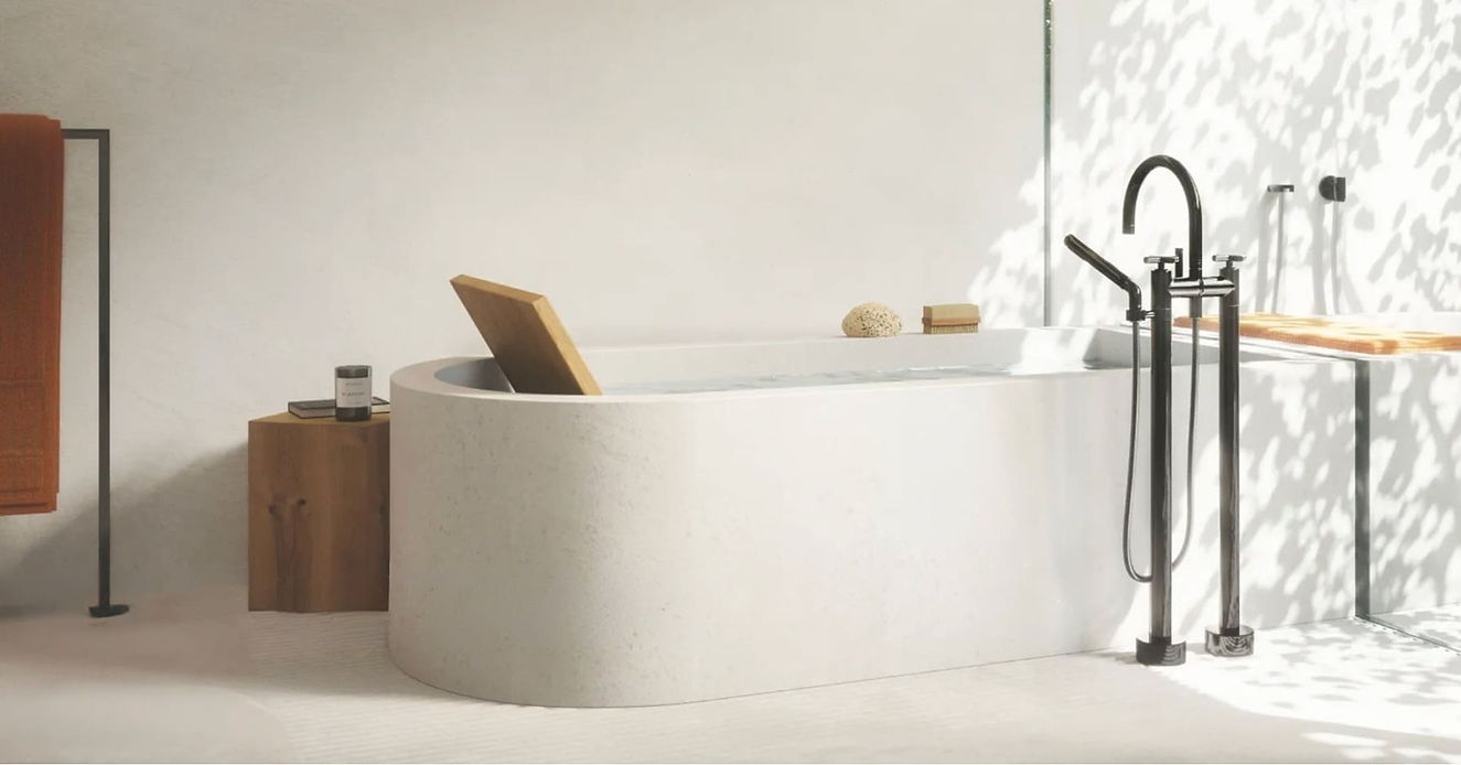 Freestanding white oval bathtub with modern black floor-standing mixer tap in a luxury bathroom
