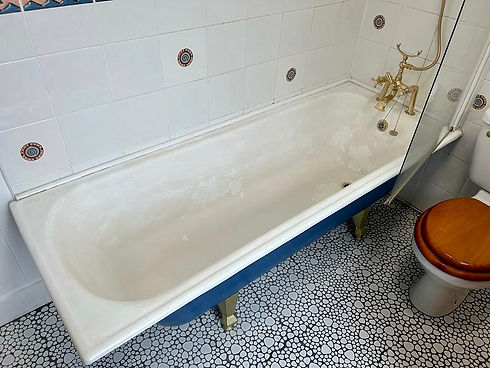 A bathroom with a bathtub and white tiled wall
