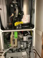 Inside view of a water heater displaying pipes, electronic components, and wiring connections within the unit