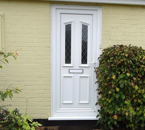 White door with diamond-patterned glass panes on a pale yellow brick wall