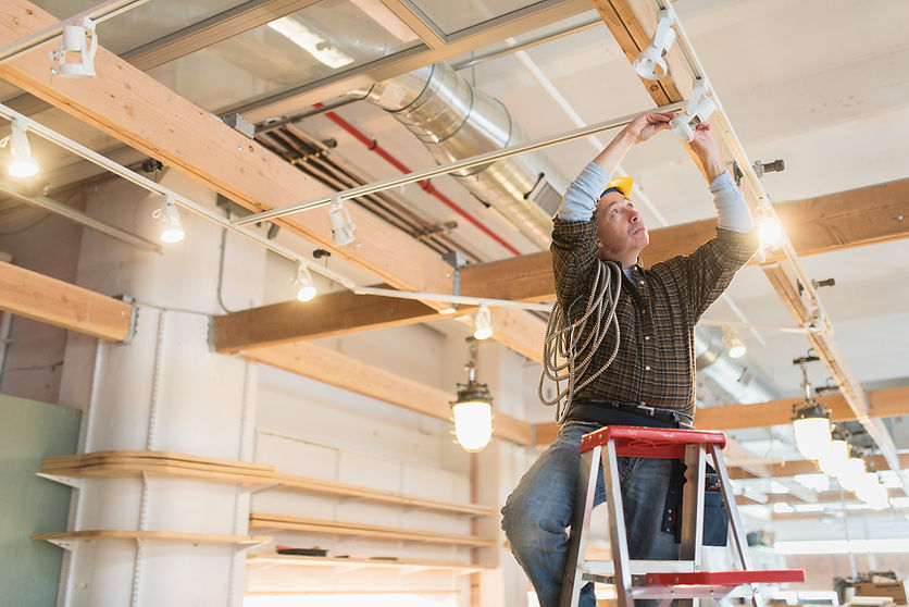 A professional installing ceiling lights in a commercial space