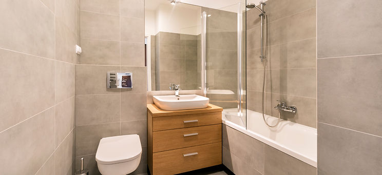 Modern bathroom with wooden vanity grey tiles floating toilet and bathtub shower