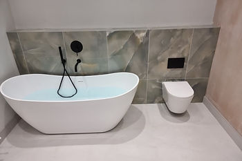 A white bathtub and a toilet in a bathroom