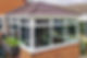 A modern brick conservatory with large white-framed windows and a brown tiled roof