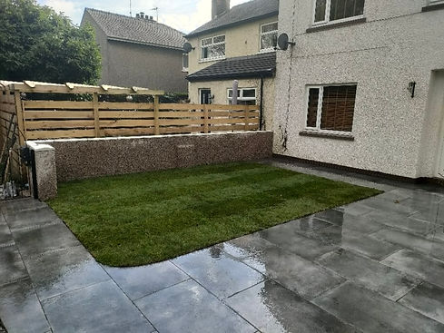 A small patch of lawn surrounded by a stone-paved patio