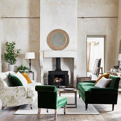 Elegant living room with green velvet chairs, a floral sofa, and a central fireplace
