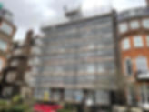 A building under renovation is covered in scaffolding with safety netting