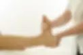 Close-up of a practitioner holding and supporting a patient's bare foot during a clinical