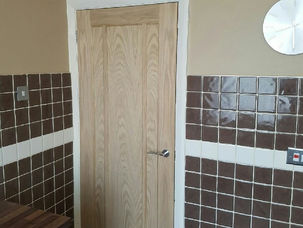 Oak panelled door fitted in a tiled bathroom