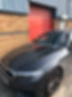 Dark grey BMW with windshield repair rig mounted on bonnet outside garage