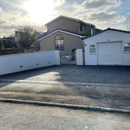 The sun shining on an expertly laid driveway in front of a garage painted in white