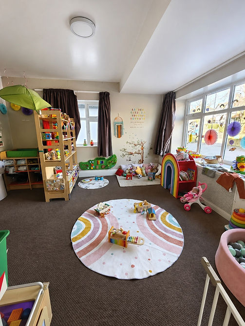Well lit nursery playroom with a wooden climbing frame next to a colourful rainbow wall mural