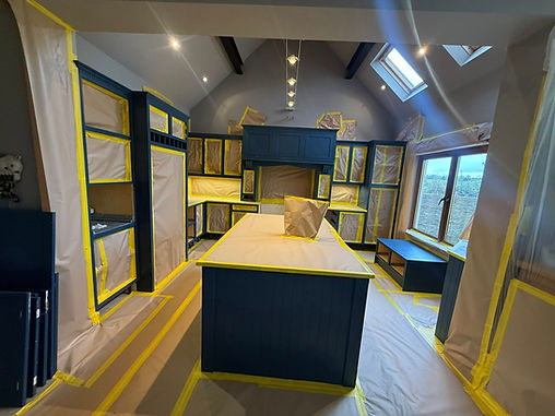 Kitchen interior under renovation, with cabinets and counters covered in protective sheets