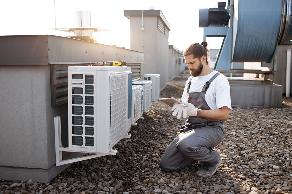 Technician using a tablet while kneeling beside an outdoor air conditioning unit on a rooftop