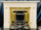 An elegant fireplace with gold detailing, silver tools, and a marble base, set against a dark backdrop