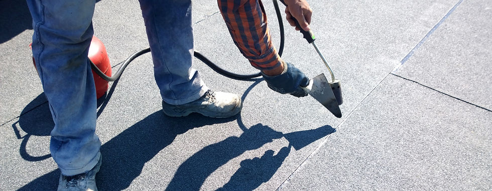 Roofer preparing part of the bitumen roofing felt roll for melting by the gas heater torch flame