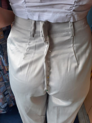 Close-up of a person wearing white pants being altered with pins placed along the back seam for adjustments