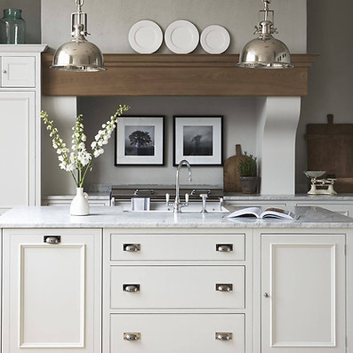 Bright, modern kitchen with white cabinets, marble-topped island, and two wooden high chairs