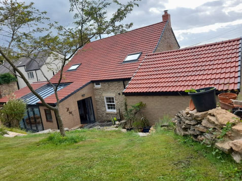 A house with a red-tiled roof, surrounded by a green lawn