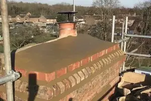 Bricked chimney with a metal cap on a rooftop