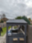 Finished grey slate roof of a garden gazebo structure surrounded by green trees under an overcast sky
