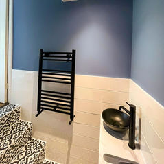Navy blue bathroom wall with black towel radiator and modern basin
