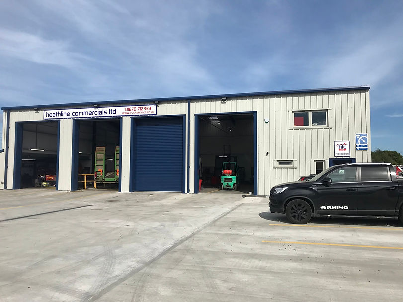 Heathline Commercials Ltd industrial unit with large workshop bay doors and a black pickup truck parked outside