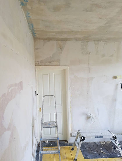 Interior room during plastering preparation showing door frame and stepladder
