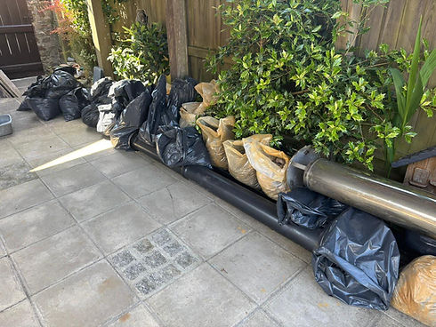 Bagged garden waste and rubbish lined up along a patio fence ready for collection during a garden clearance in Torquay