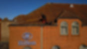 A worker cleaning the rooftop of a commercial space with a long pole, secured with safety gear