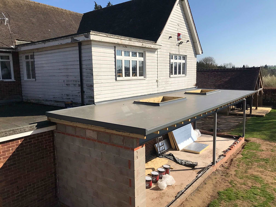 Single-story house extension under construction, featuring a flat roof and brick walls