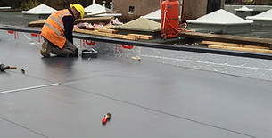 Roofer working on flat roof repair and waterproofing installation