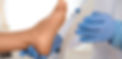 Close-up of a clinical professional wearing blue gloves supporting a patient's foot during an exam