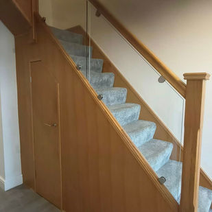Oak staircase with glass balustrade panels and grey carpet